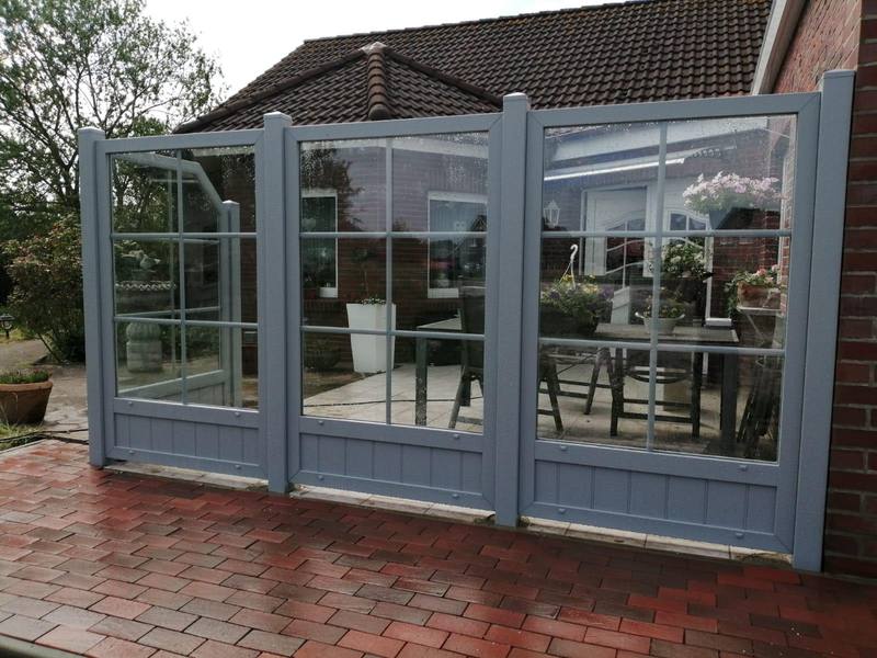 Windschutz aus Glas mit grauen Rahmen auf einer Terrasse